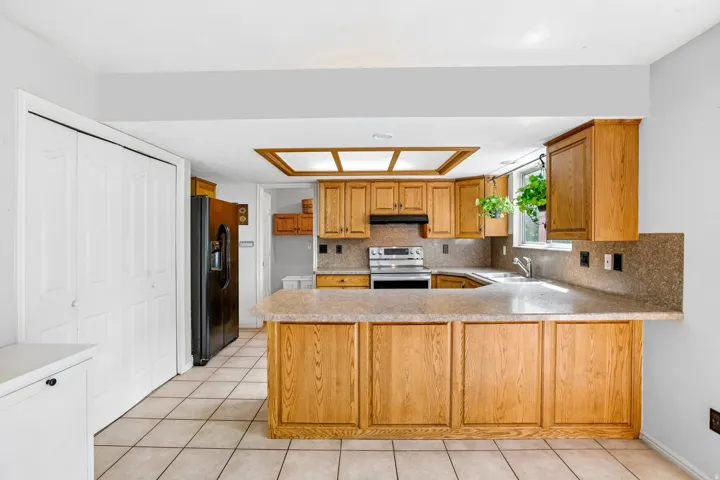 Kitchen featuring wood-finish cabinetry, tile flooring, a breakfast bar, and a double-door pantry