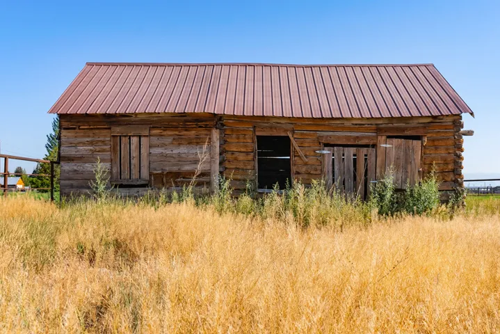 Rustic log cabin structure with a red metal roof and natural wood siding