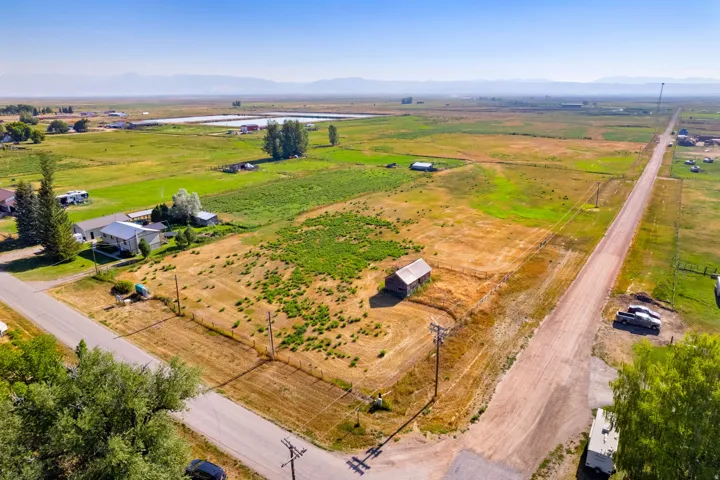 Expansive land parcel with surrounding agricultural fields, distant mountains, and a visible barn structure