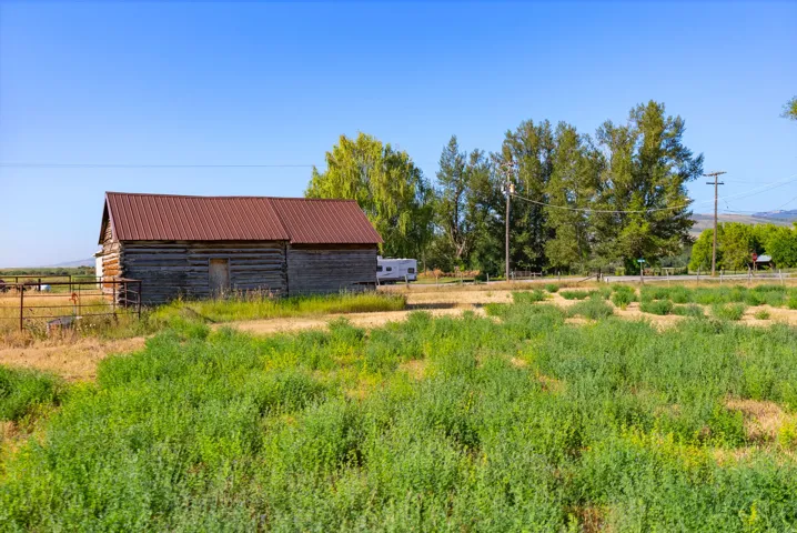 Log cabin structure with a metal roof and fenced perimeter