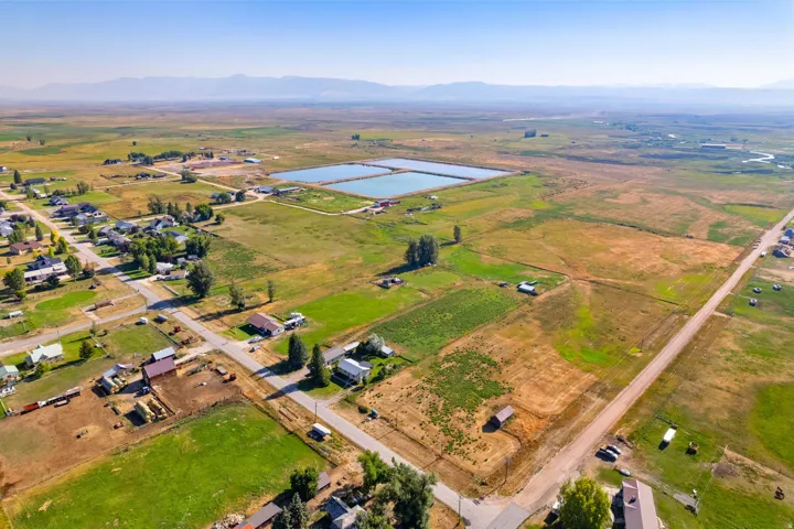 Expansive rural landscape featuring two water reservoirs, mountainous background, and scattered residential properties