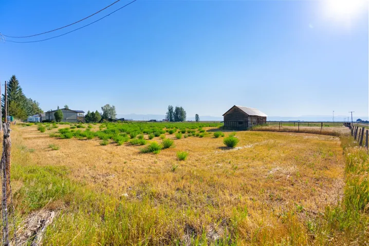 Expansive open land with a rustic wooden barn and a wooden post fence