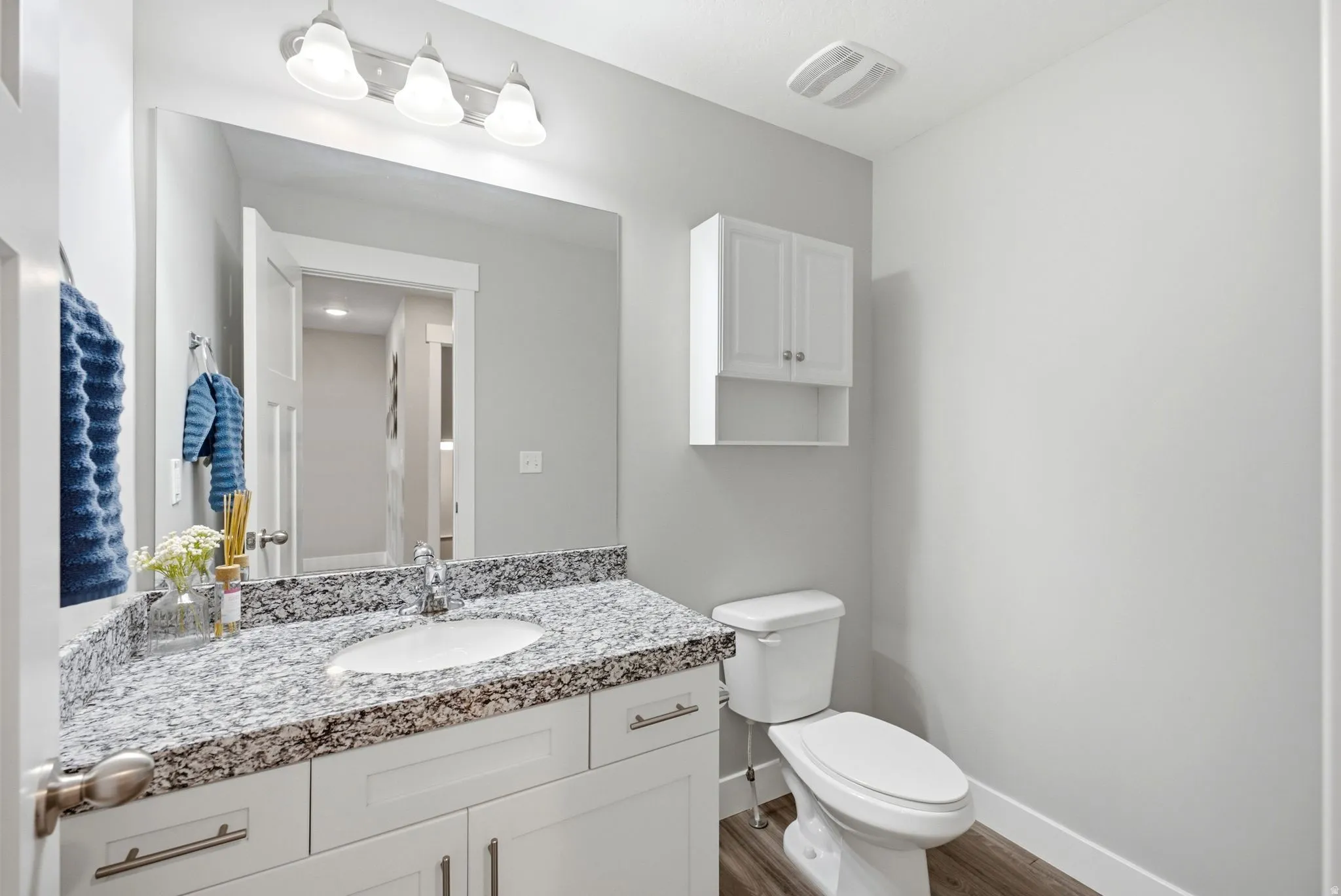 White vanity with integrated sink, speckled countertop, and brushed nickel faucet