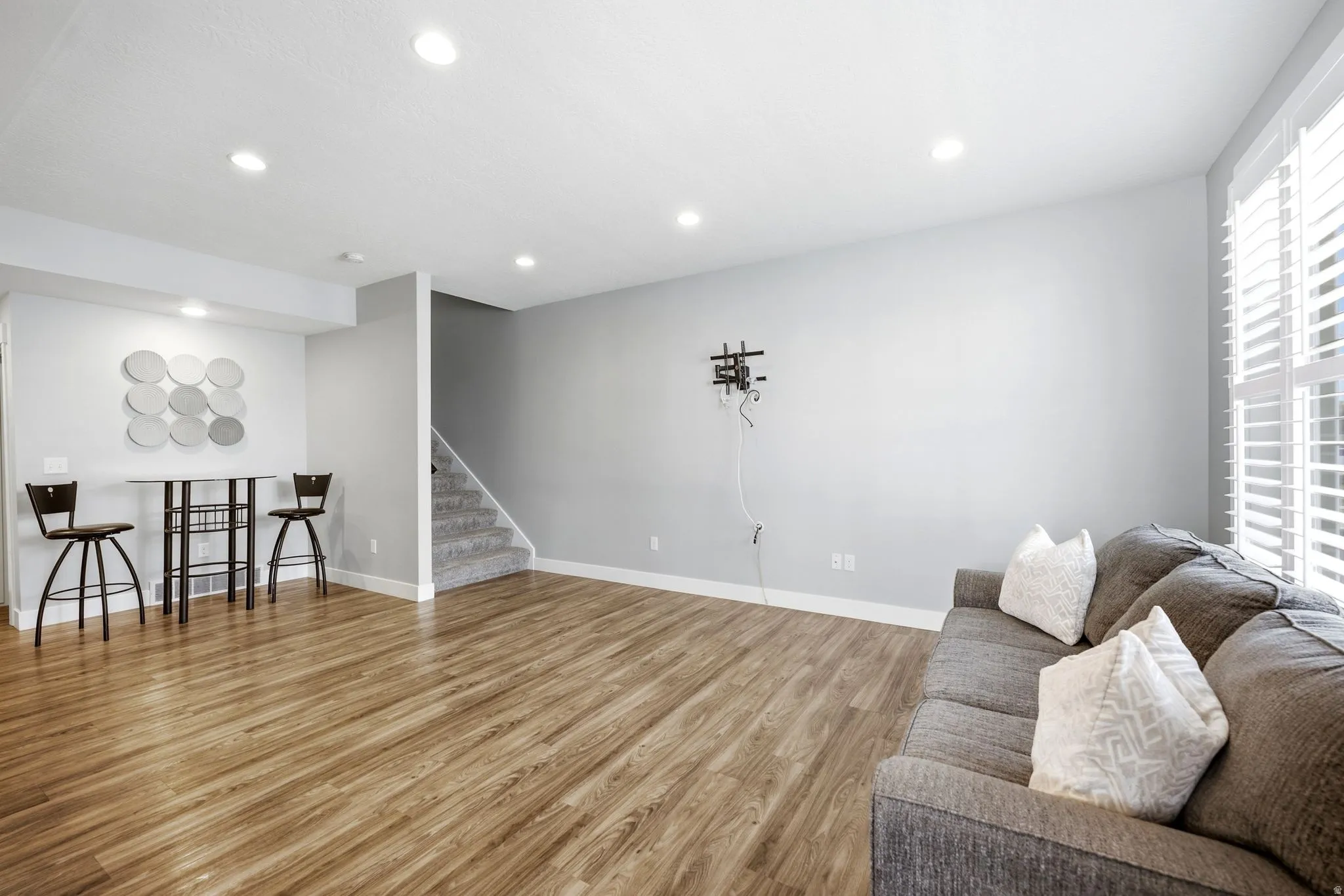 Recessed lighting, wood-finish flooring, white plantation shutters, and carpeted stairs