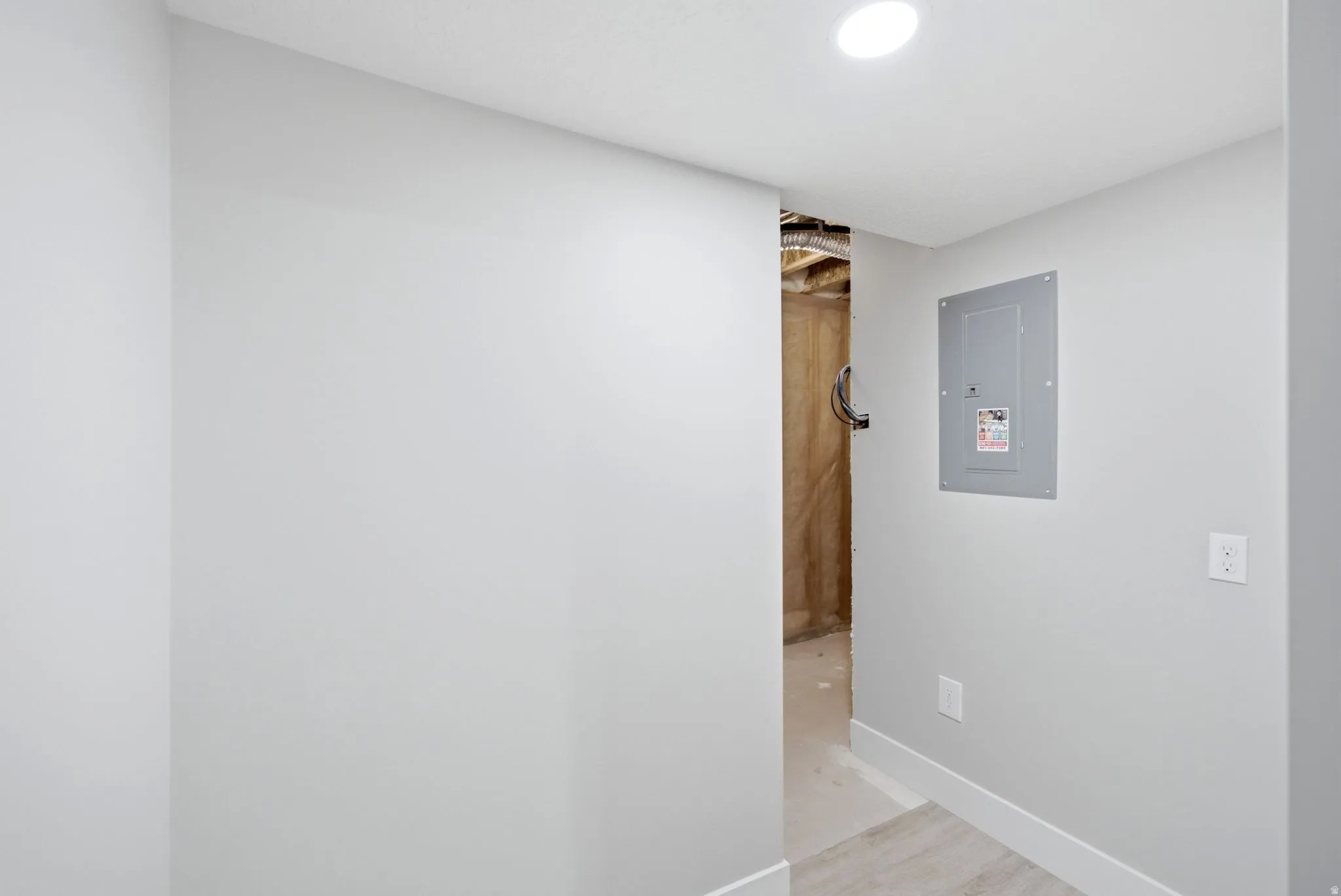 Recessed ceiling lighting, electrical panel, painted walls, and wood-finish flooring