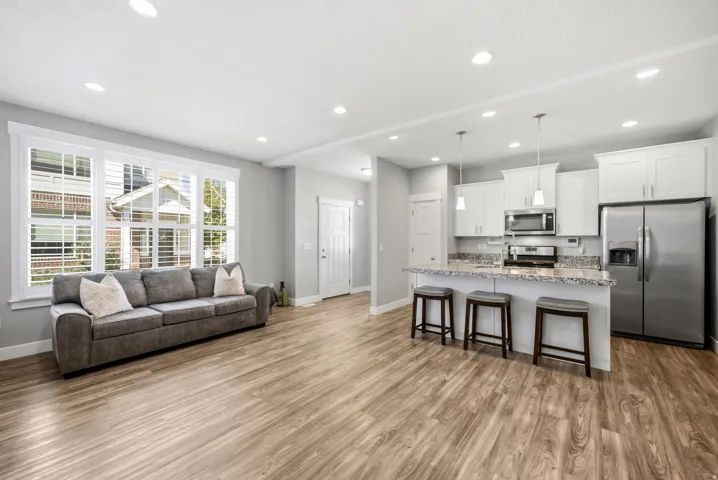 Open-concept living area featuring wood-finish flooring, recessed lighting, and a kitchen island with stone countertop