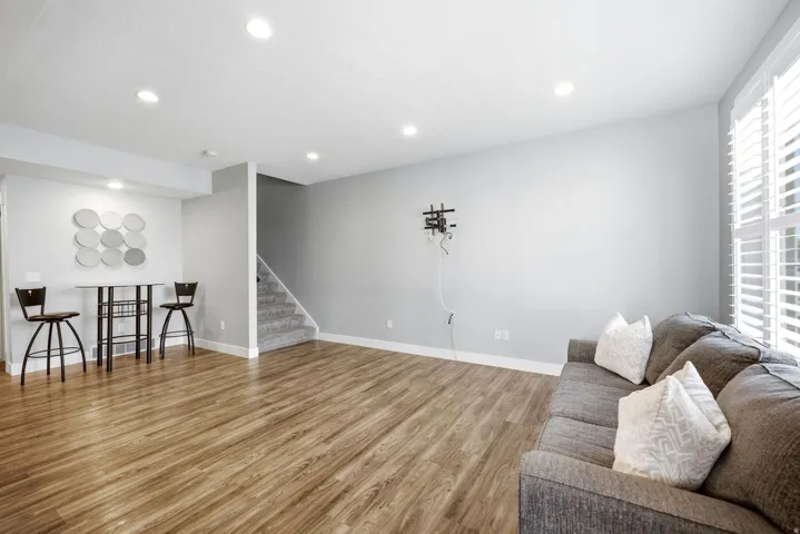 Recessed lighting, wood-finish flooring, white plantation shutters, and carpeted stairs