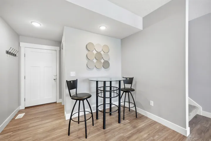 Recessed ceiling lighting, durable wood-finish flooring, and a white interior door with panel detailing