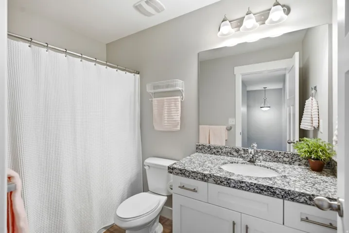 White vanity with a light-colored speckled countertop, undermount sink, and brushed nickel faucet