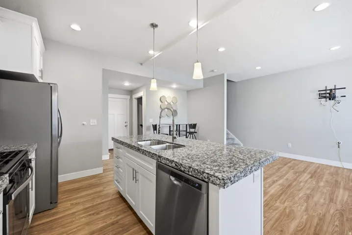 Kitchen island featuring a stainless steel sink, a stainless steel dishwasher, and a light-toned countertop
