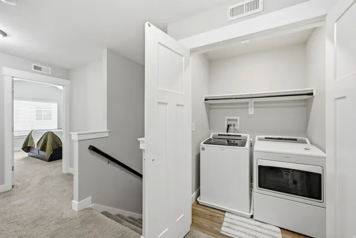 Dedicated laundry closet with wood-finish flooring and an integrated shelving unit