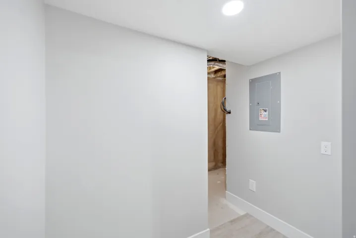 Recessed ceiling lighting, electrical panel, painted walls, and wood-finish flooring