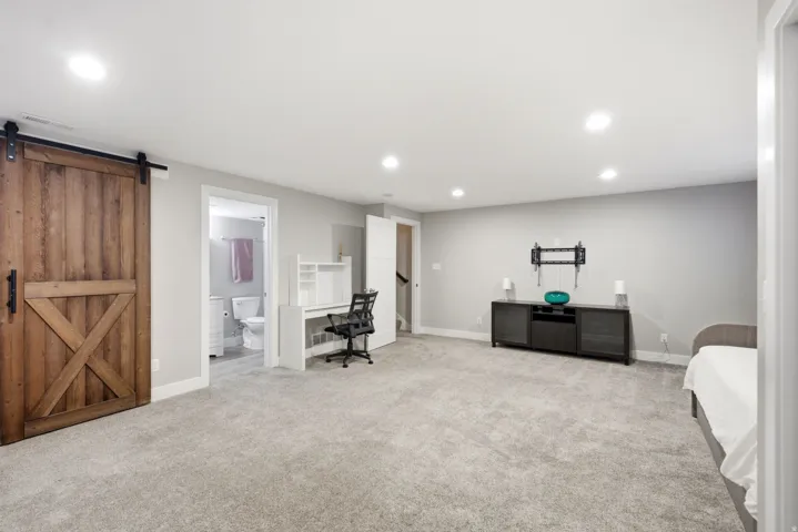 Carpeted flooring, recessed lighting, wood-finish barn door, and a built-in desk