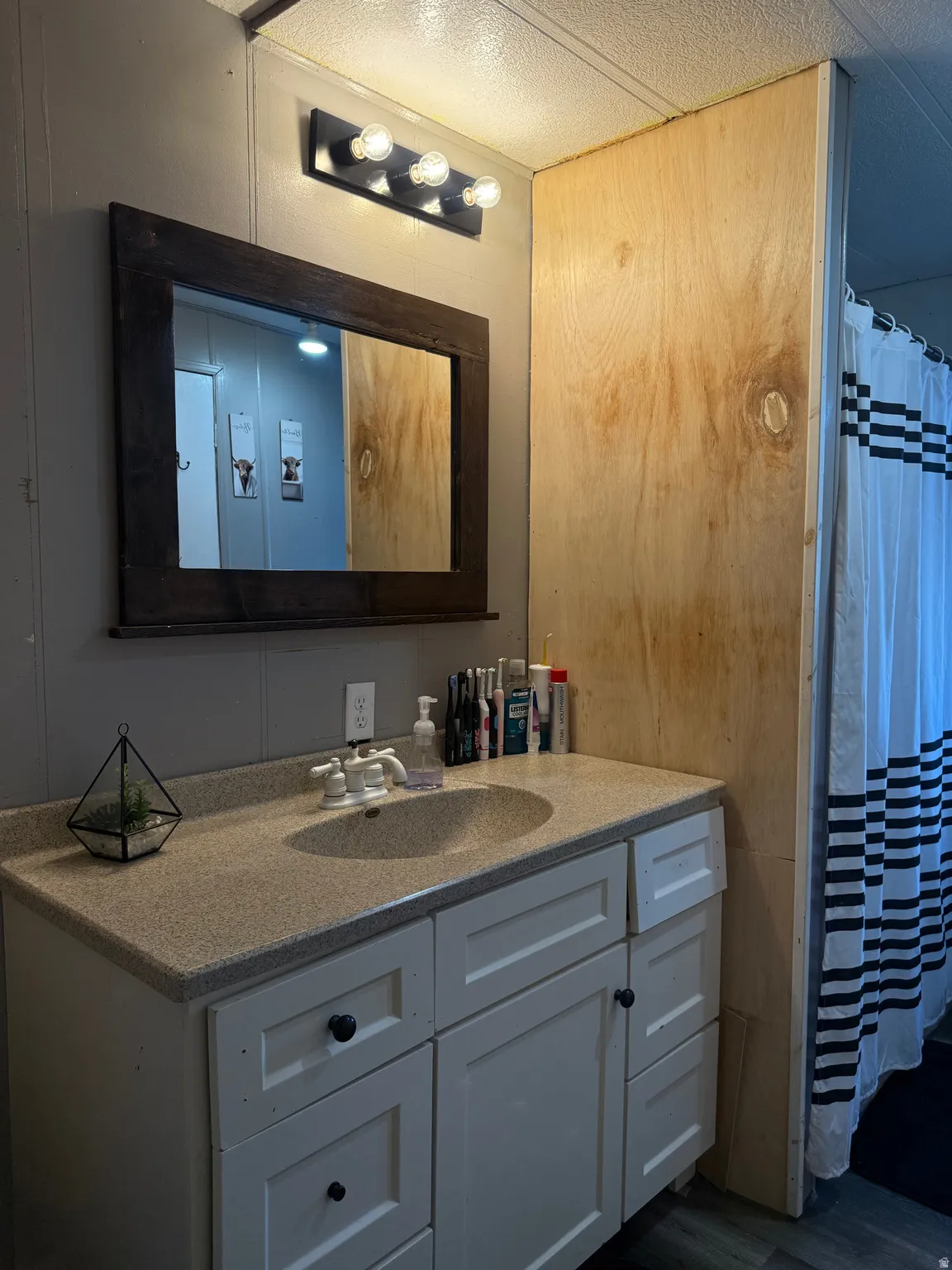 White vanity with a speckled countertop and an oval basin