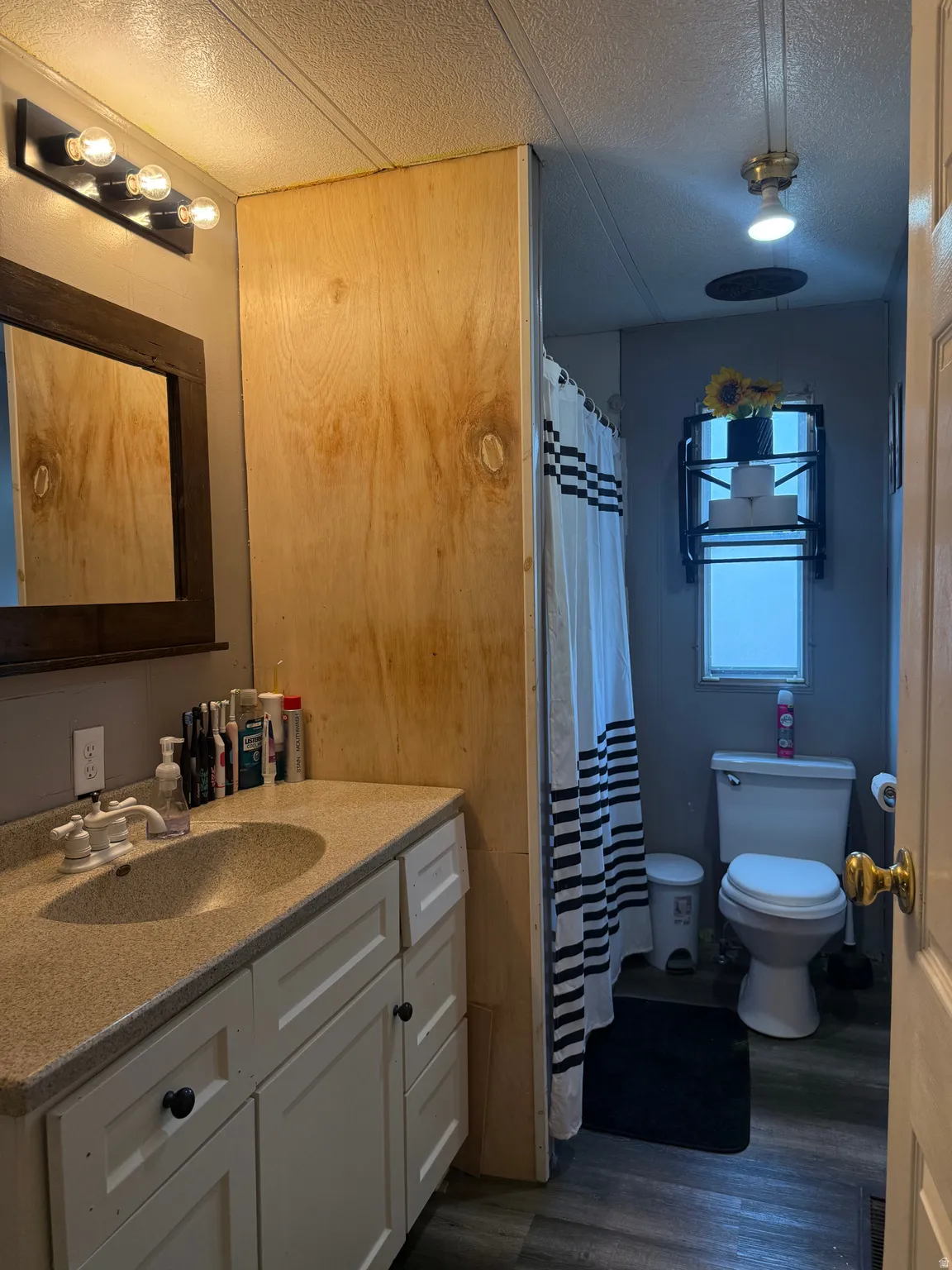 Vanity with integrated sink and chrome faucet, framed mirror, and three-bulb vanity light fixture