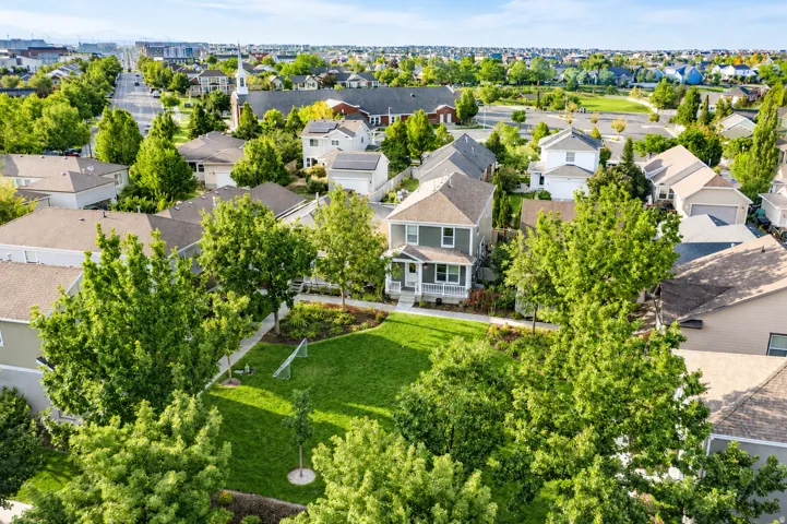 Green exterior with a covered porch, surrounded by lush trees and a manicured lawn