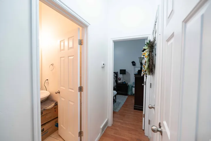 Hallway featuring wood-finish flooring, white paneled doors, and painted white walls