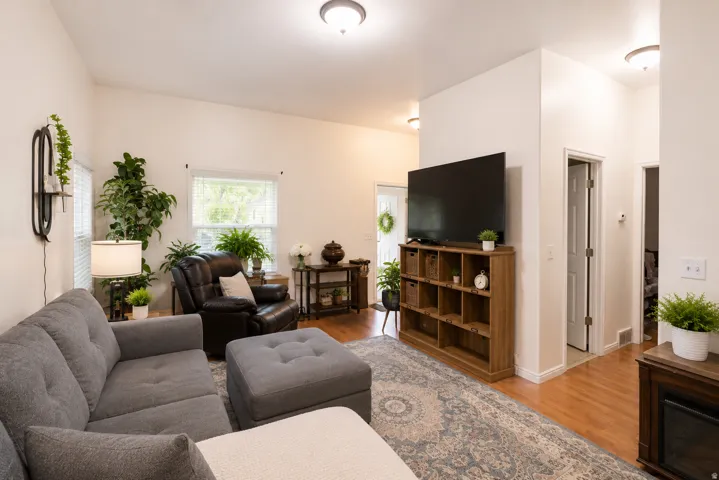 Living area featuring vaulted ceilings, wood-finish flooring, and white walls