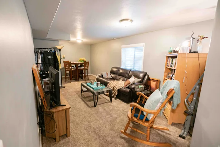 Carpeted living area with overhead lighting and a single window with blinds