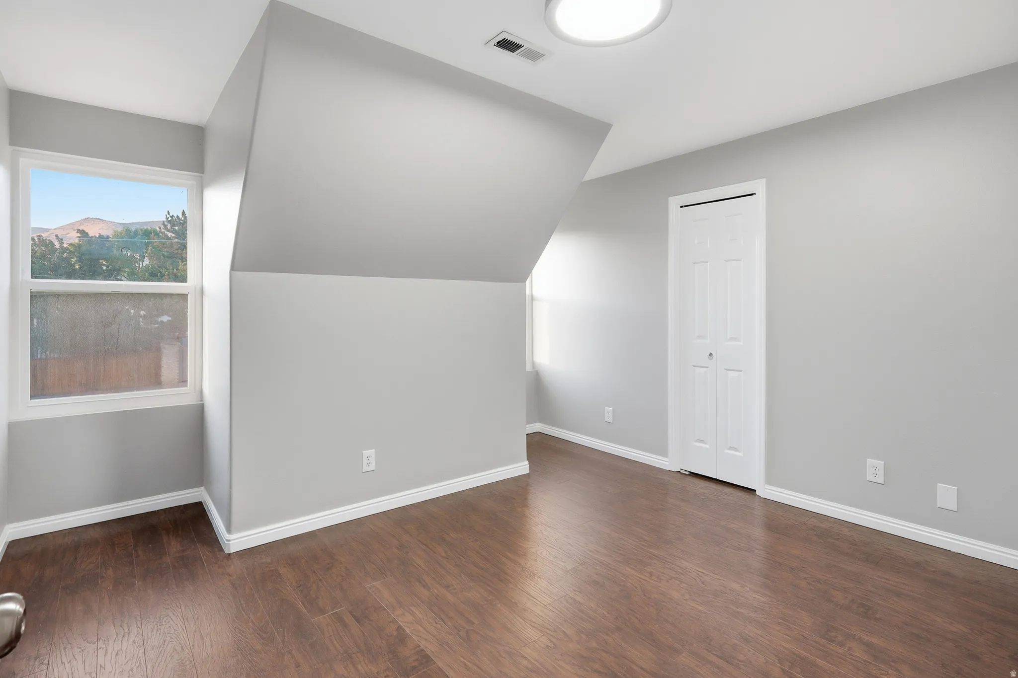 Hardwood-finish flooring, white baseboards, and a neutral wall color complement the room