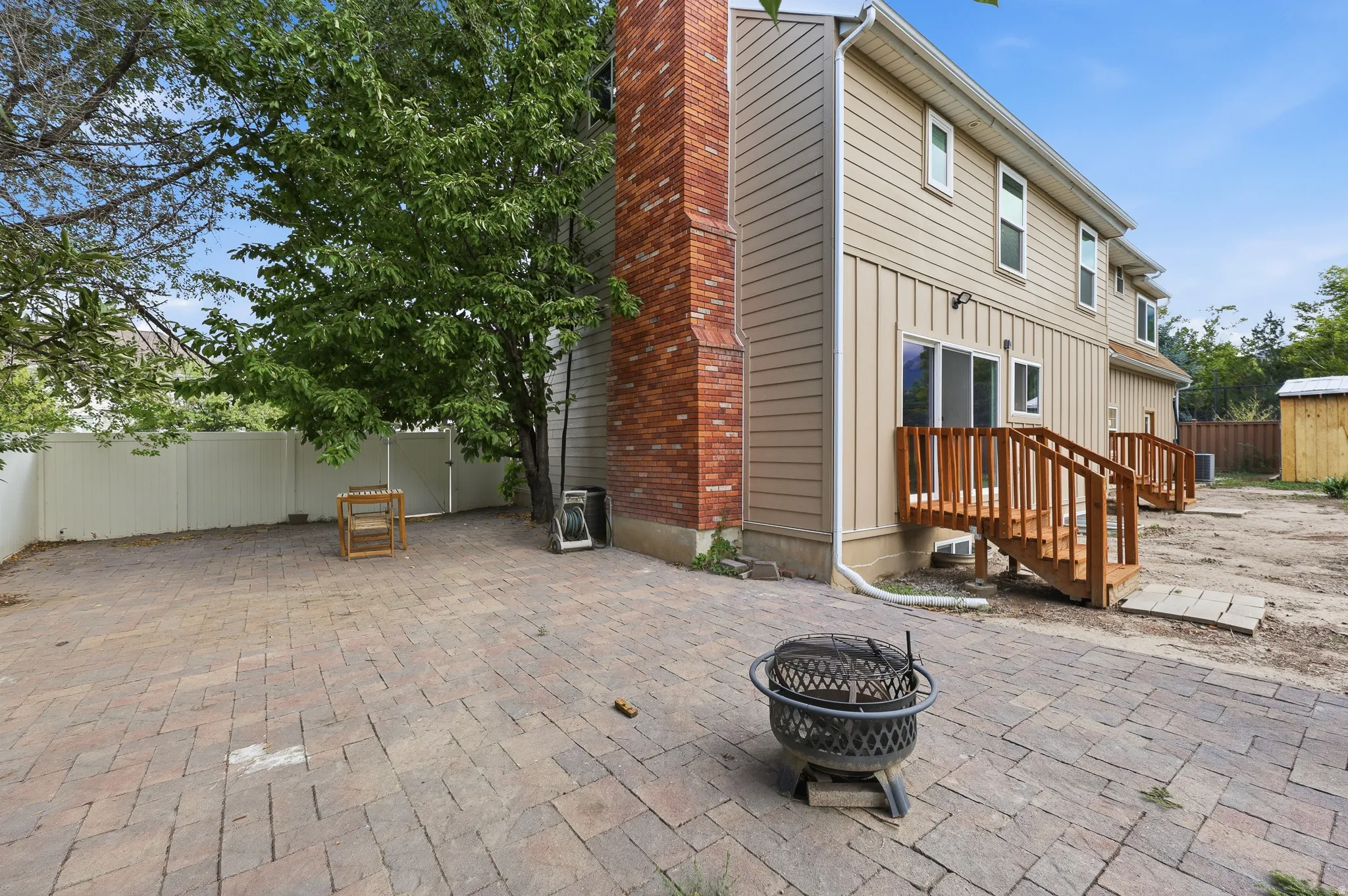 Expansive paver patio with a white privacy fence