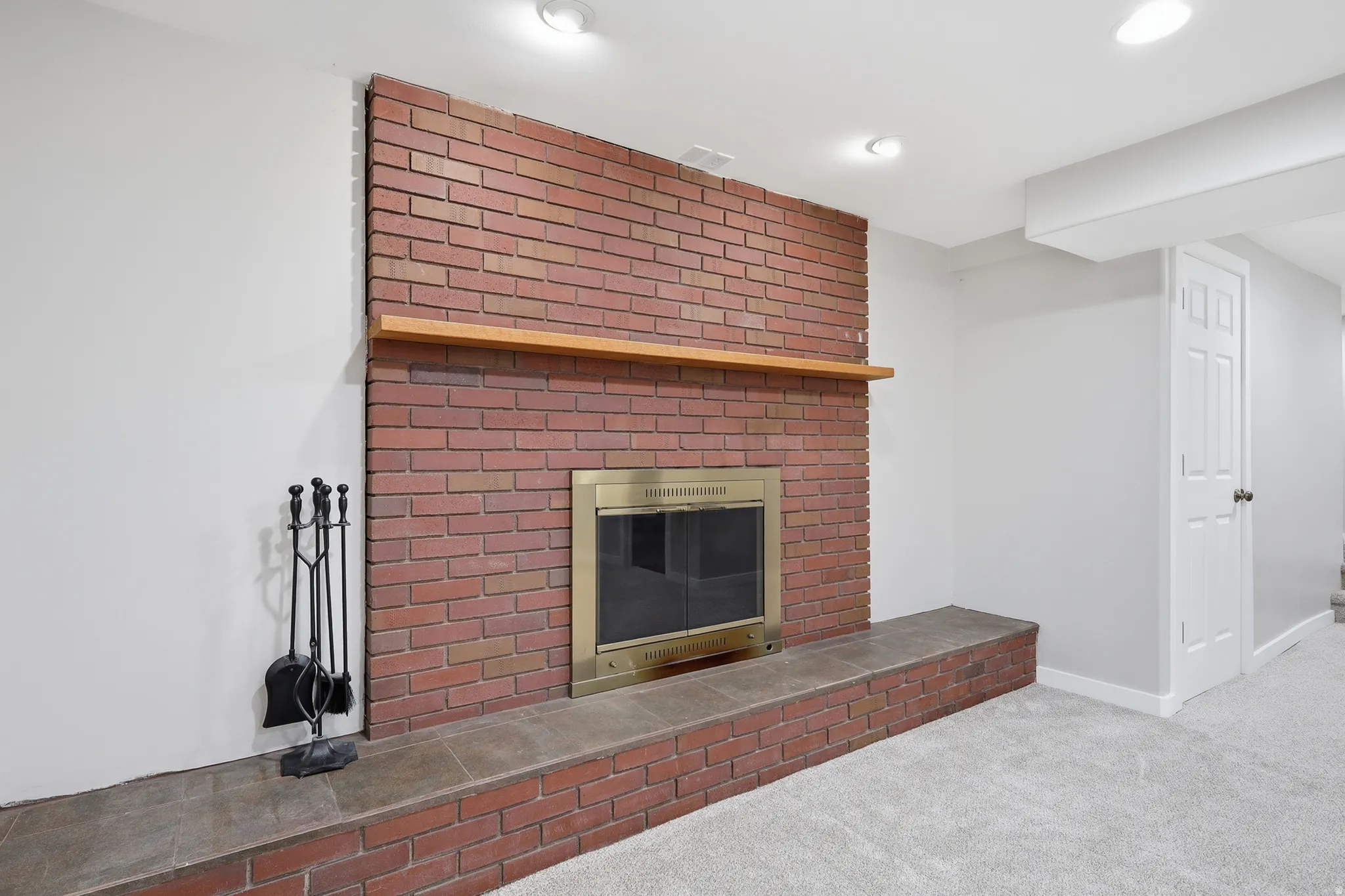 Brick fireplace with a brass firebox, stone hearth, and wood mantel