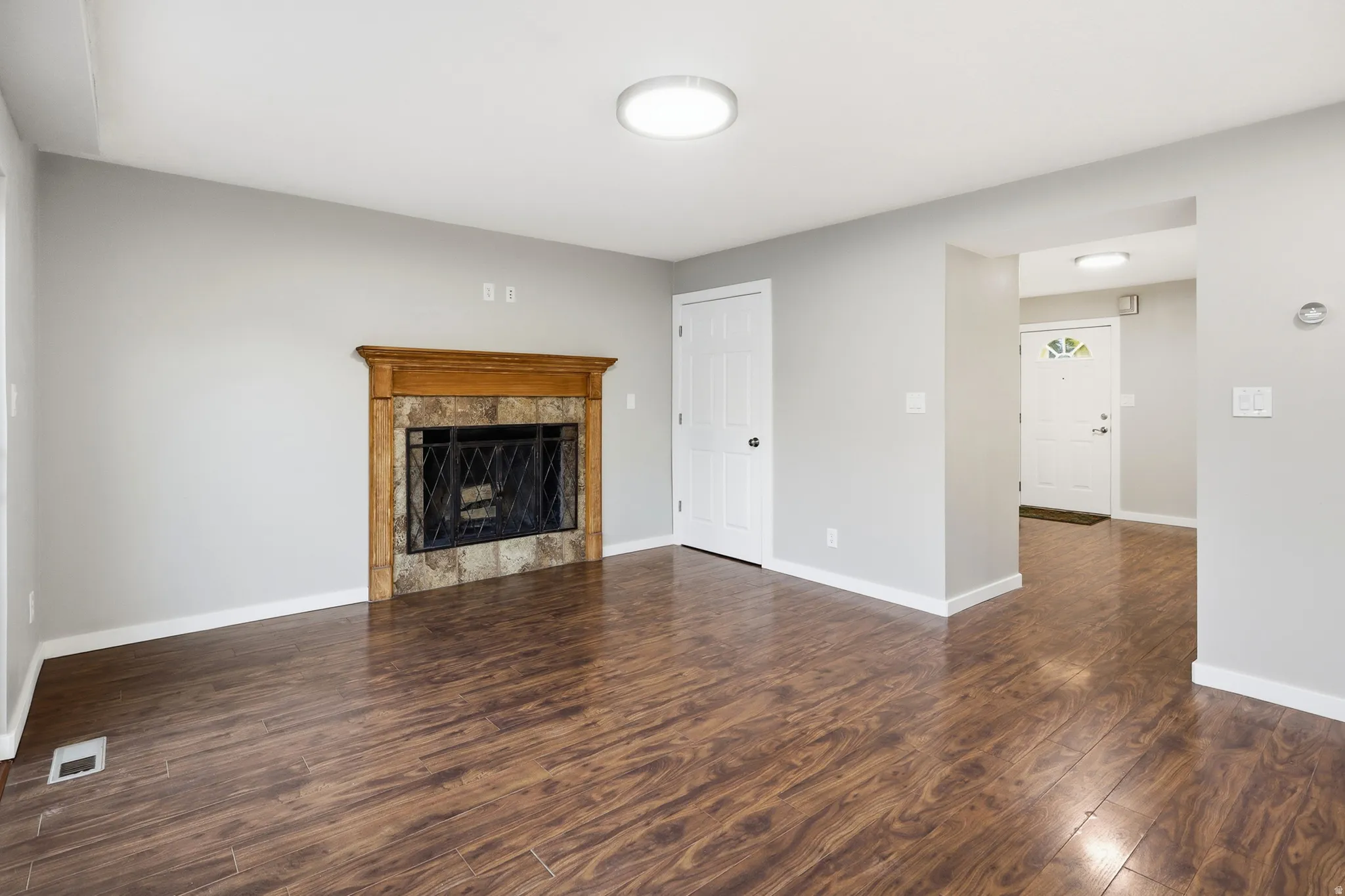 Hardwood-finish flooring, a fireplace with a wood mantle and stone surround, and a ceiling-mounted light fixture