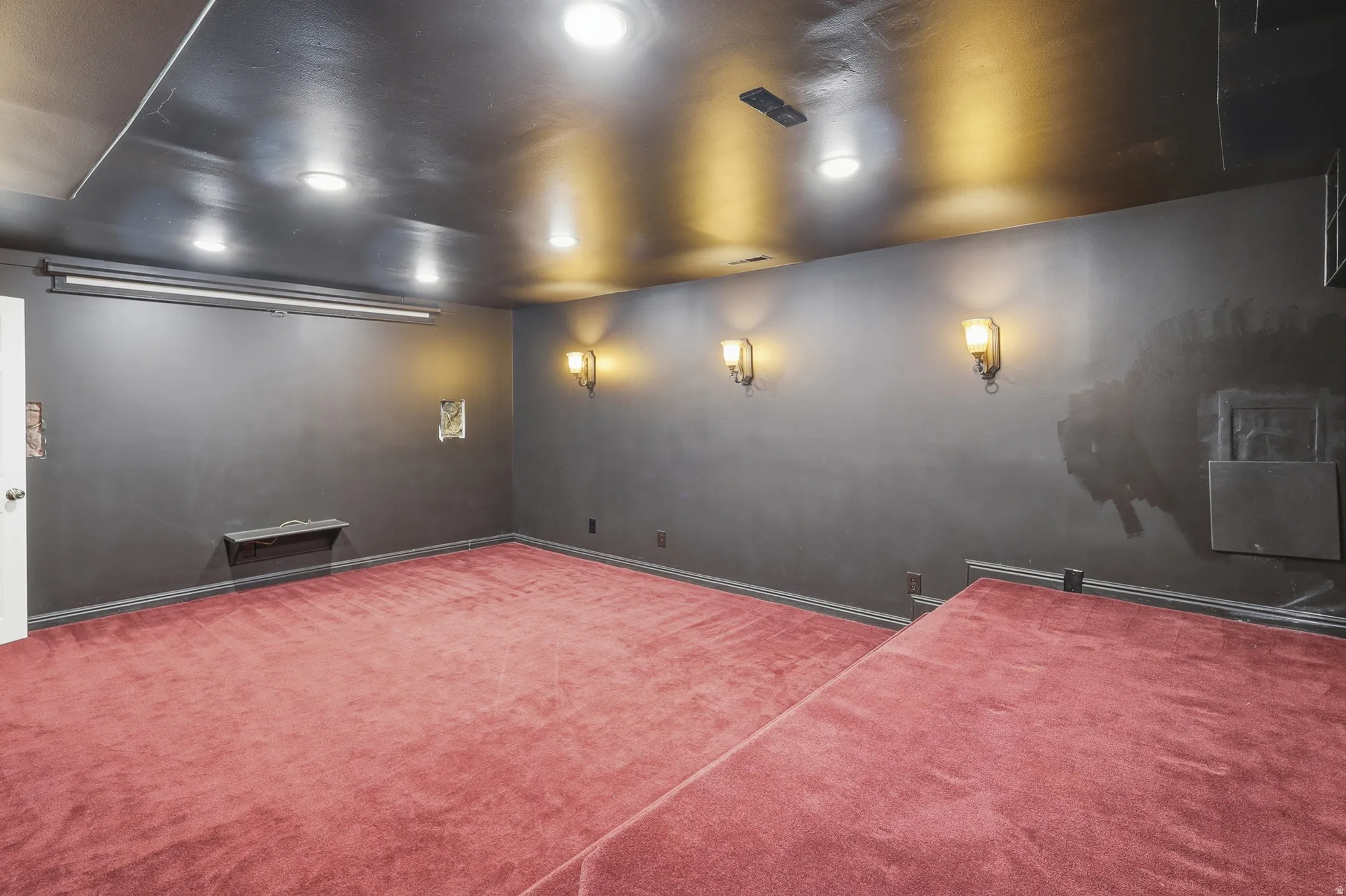 Spacious room featuring red carpeting and dark painted walls