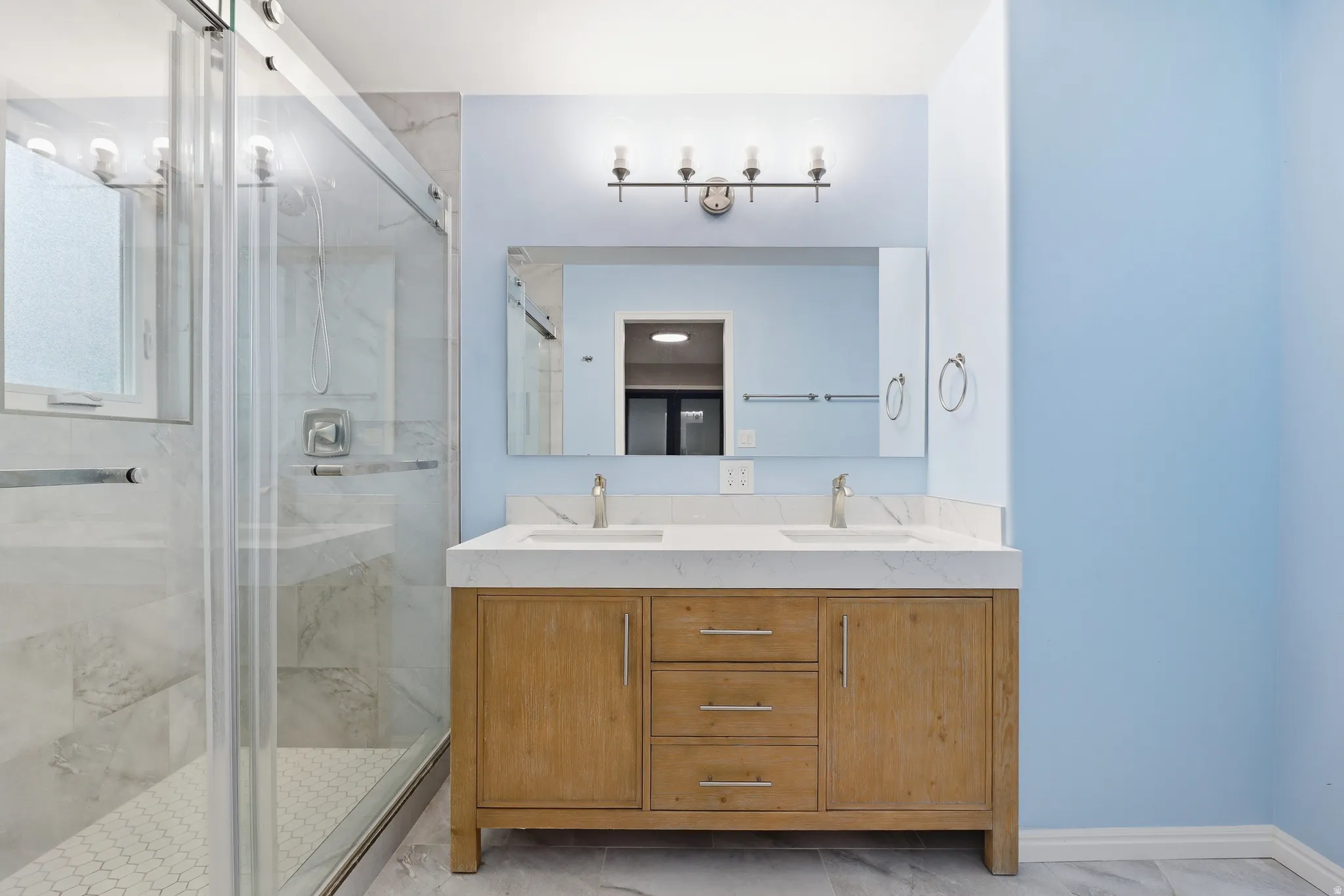 Dual vanity with light wood-finish cabinetry, white countertop, and brushed nickel fixtures