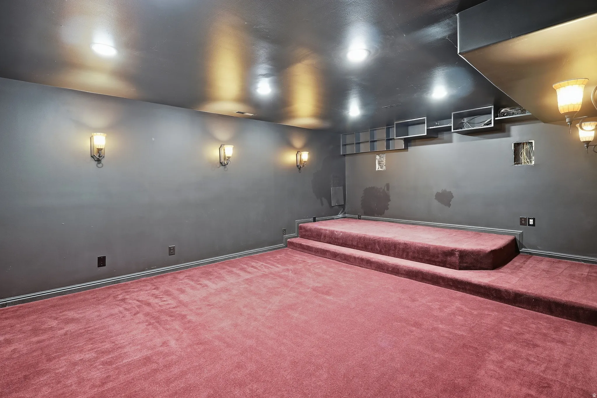 Carpeted flooring, recessed ceiling lighting, wall-mounted sconce lighting, and built-in shelving