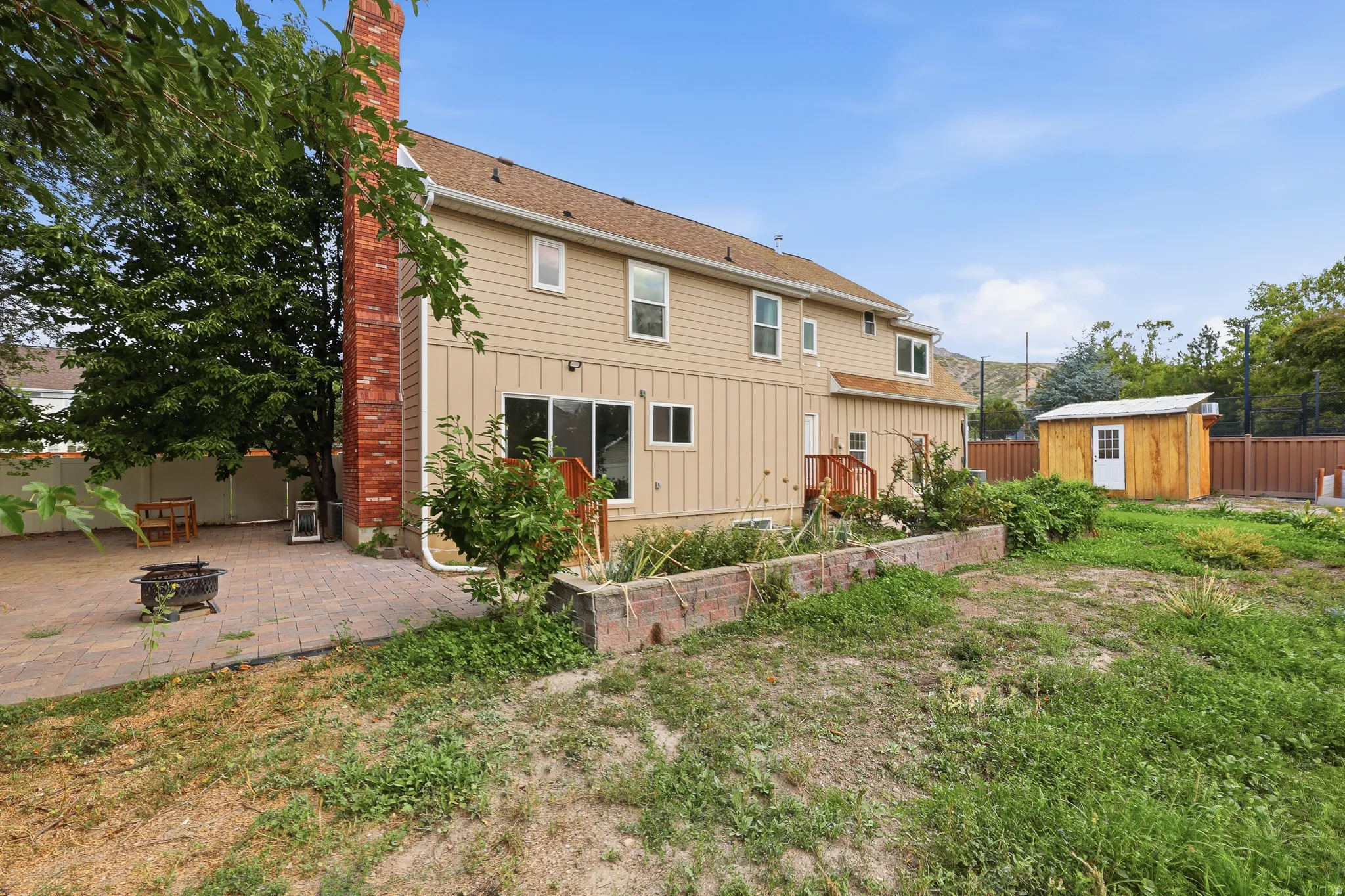Two-story exterior with siding, a brick chimney, and a ground-level patio