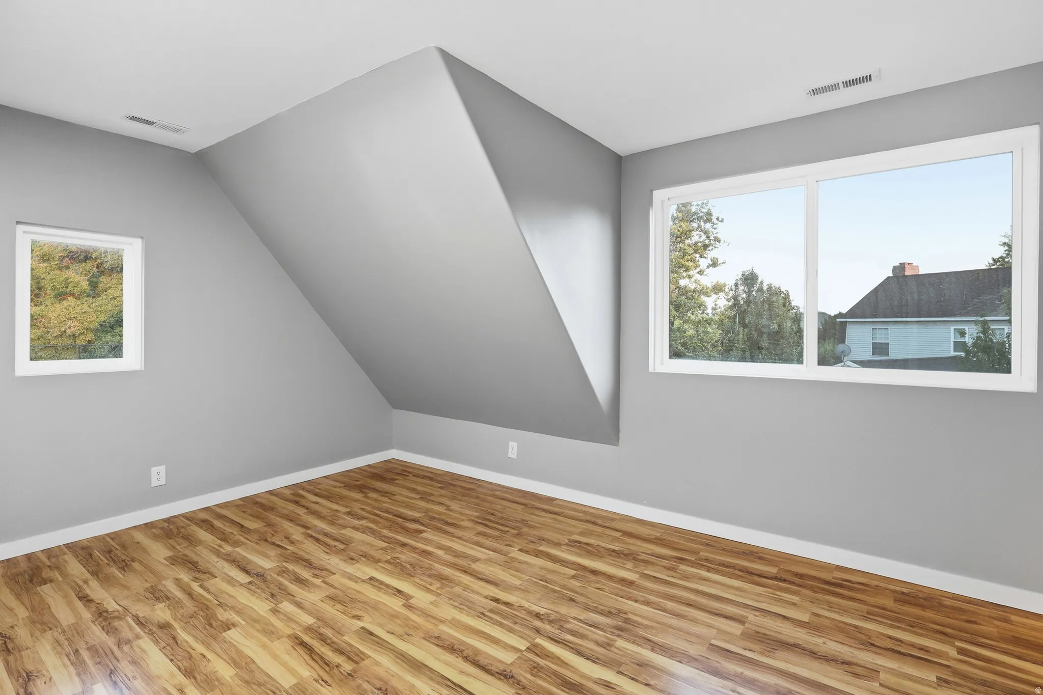 Wood-finish flooring, white trim, and two windows provide natural light