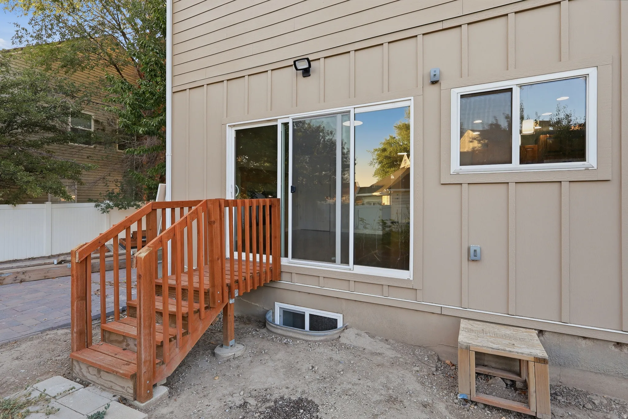 Sliding glass door access to exterior, wood deck and stairs, durable siding, and an egress window well