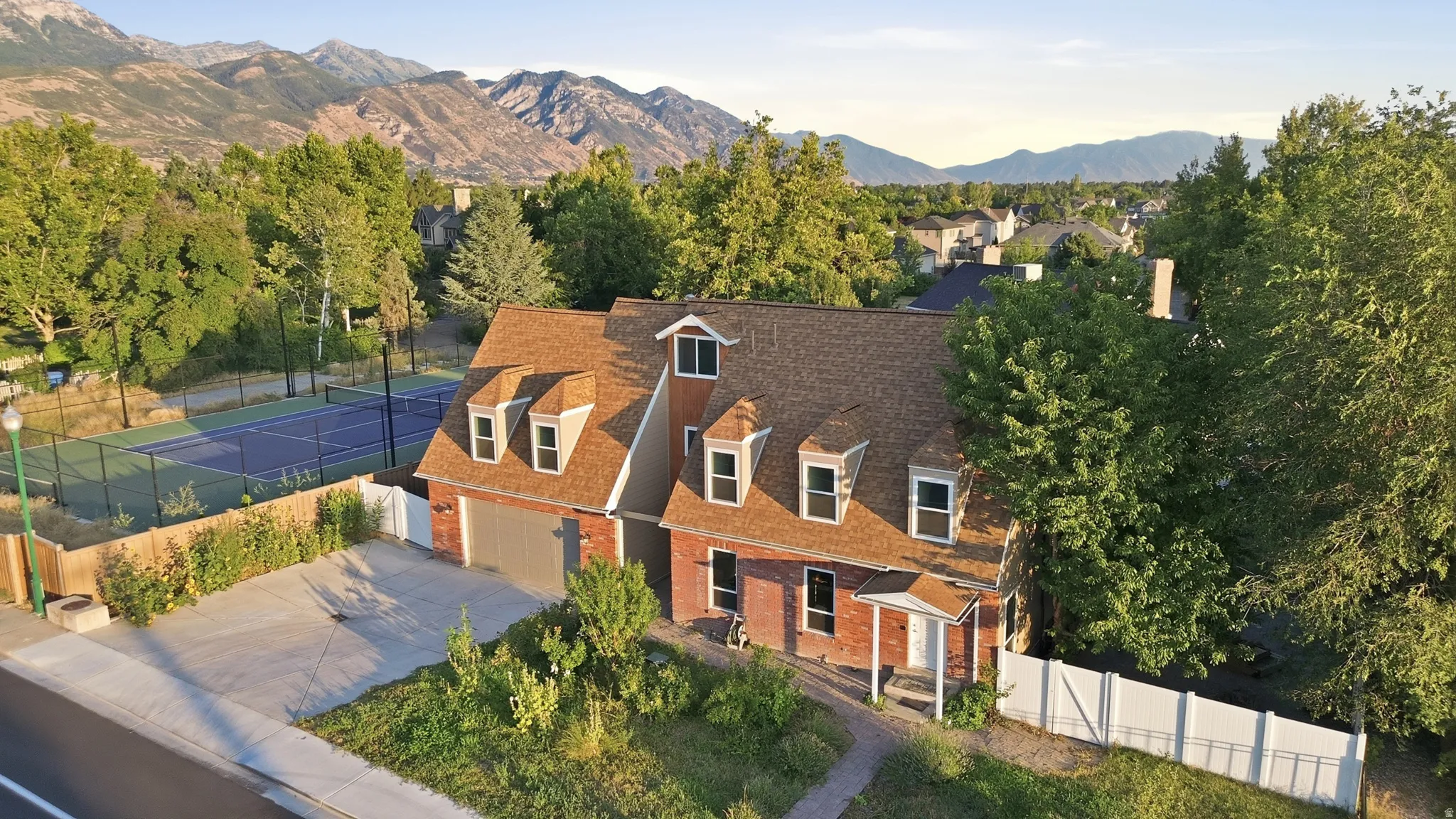 Brick exterior residence with a brown shingle roof and dormer windows