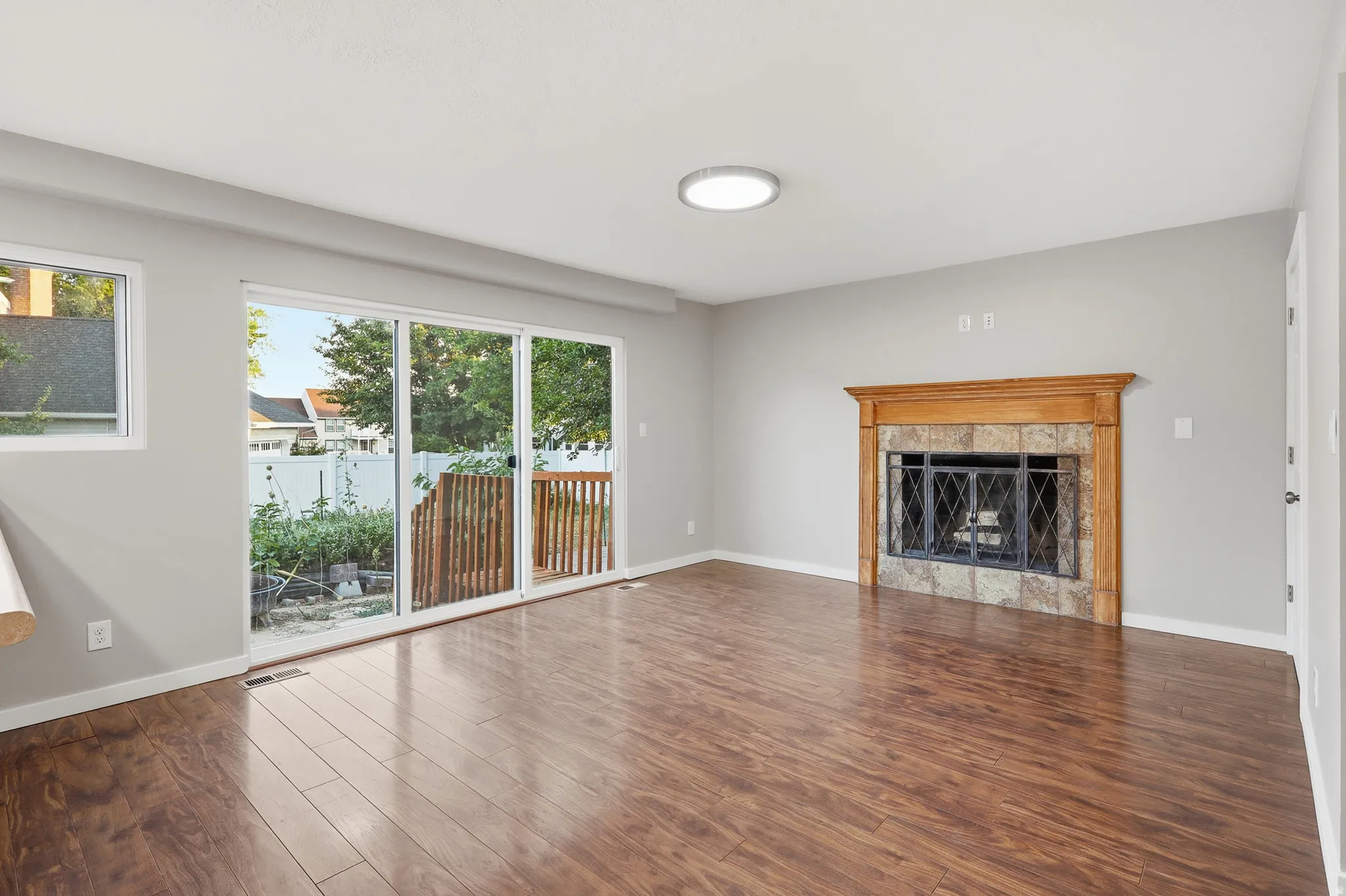 Fireplace with a wood mantle and stone surround, wood-finish flooring, sliding glass door, and a wooden deck