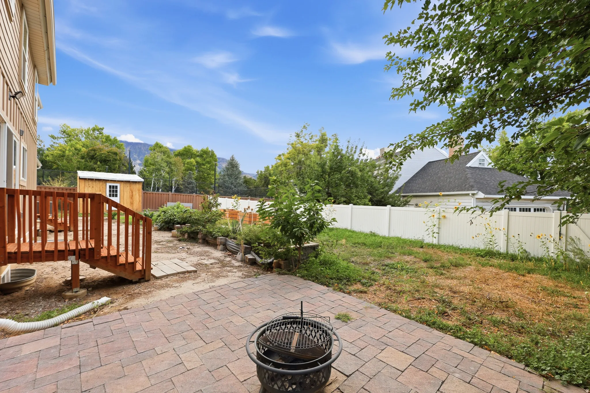 Patio area with paver stones, wooden deck, storage shed, and a privacy fence