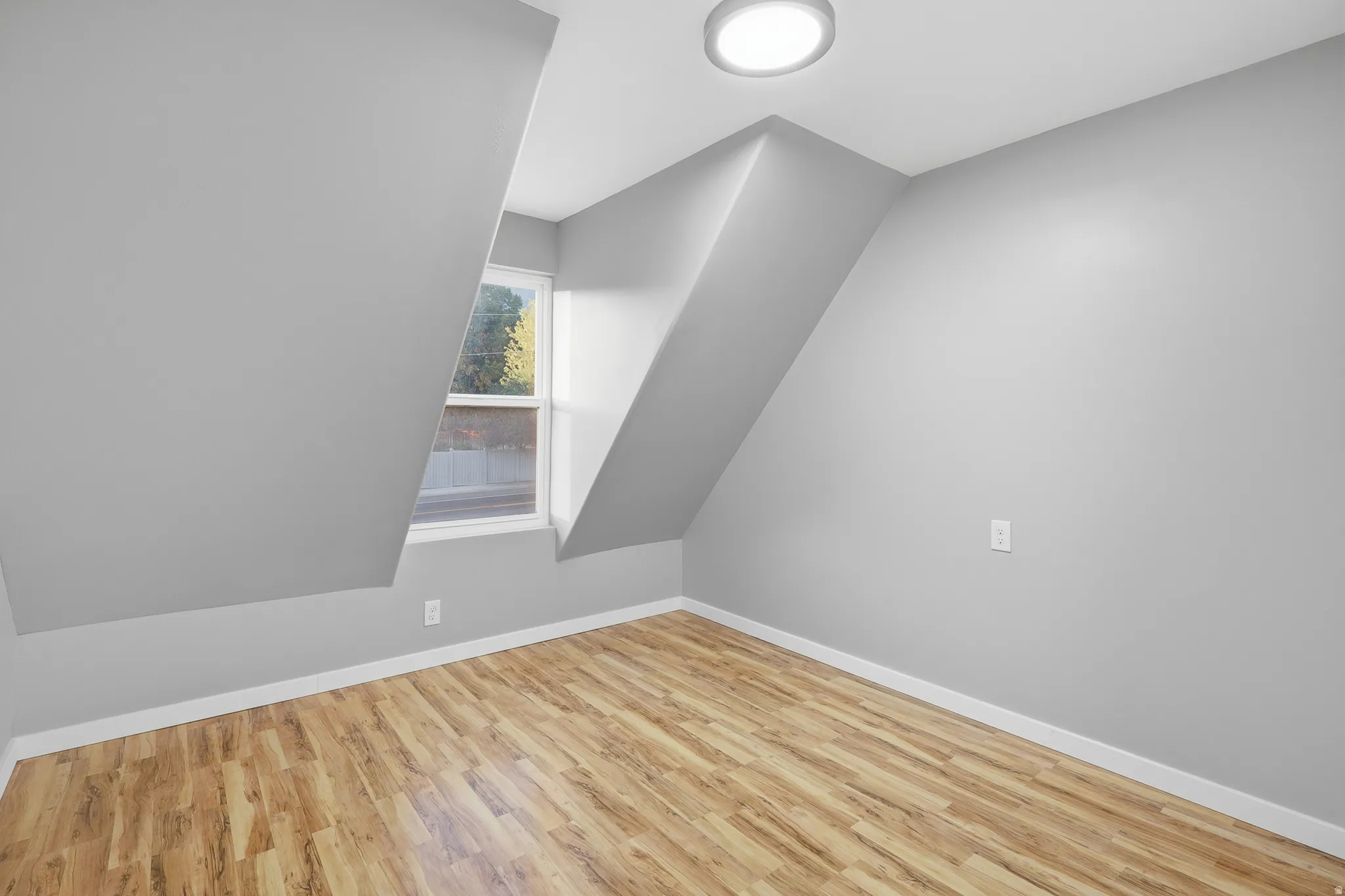 Sloped ceilings, wood-finish flooring, and a flush mount lighting fixture