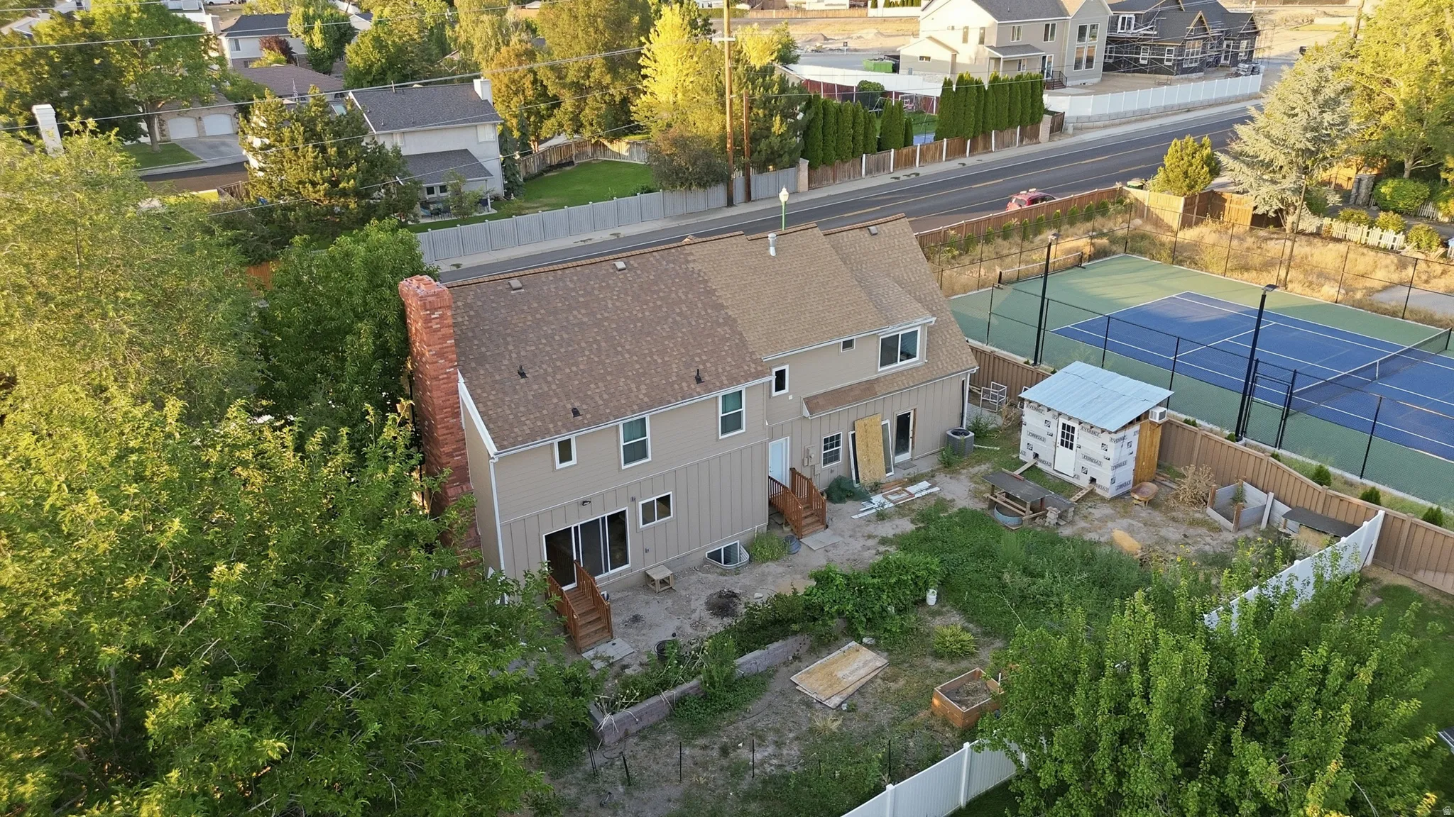 Two-story residence featuring a shingled roof, brick chimney, and rear patio doors