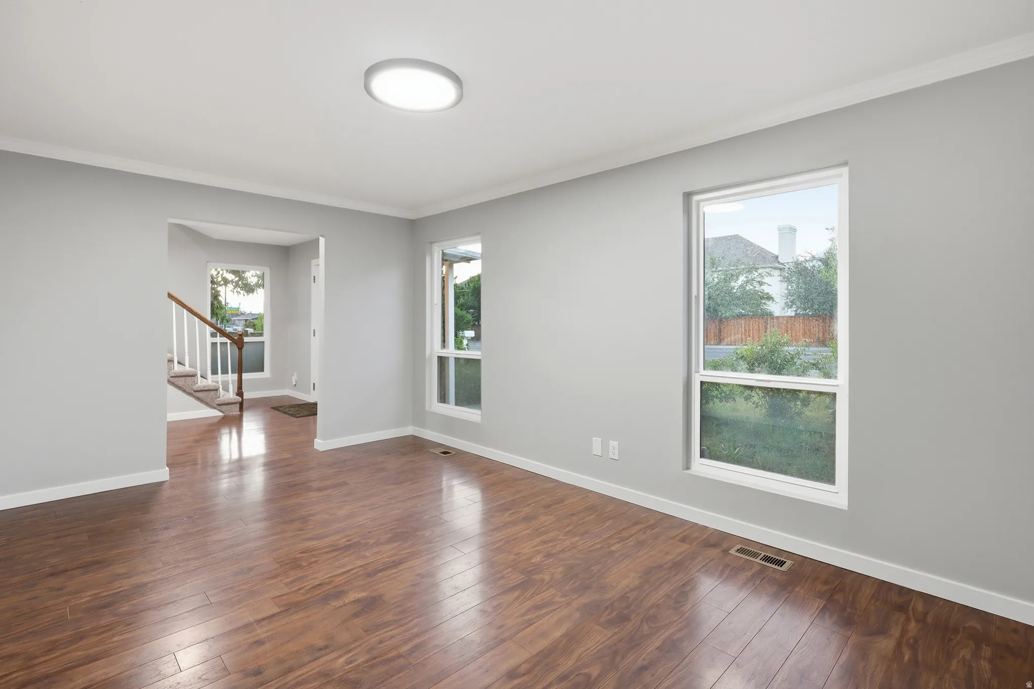 Wood-finish flooring, white trim, recessed lighting, and multiple windows with white frames