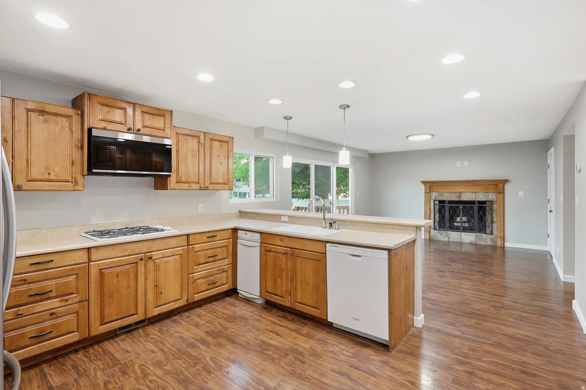Kitchen featuring wood cabinetry, stone-finish countertops, and wood-finish flooring