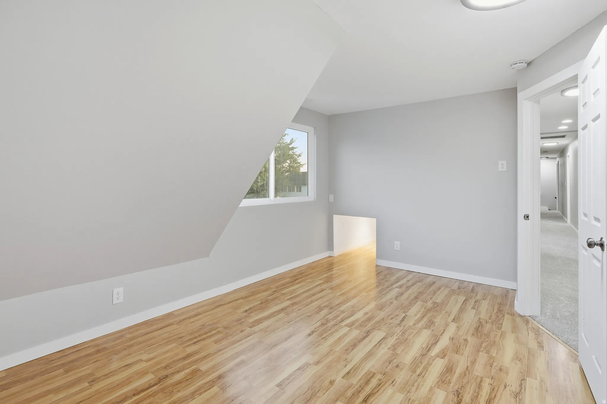 Wood-finish flooring, white trim, recessed lighting, white interior door, and a window for natural light