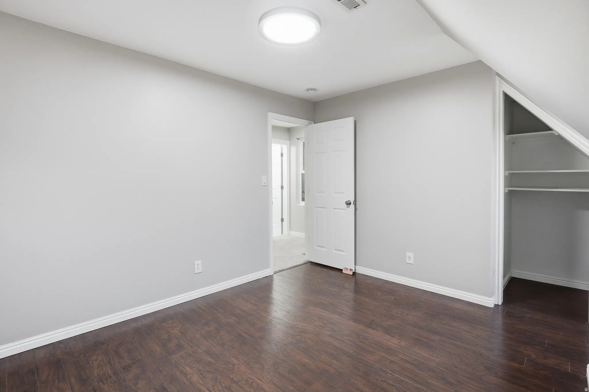Wood-finish flooring, white baseboards, and built-in closet shelving