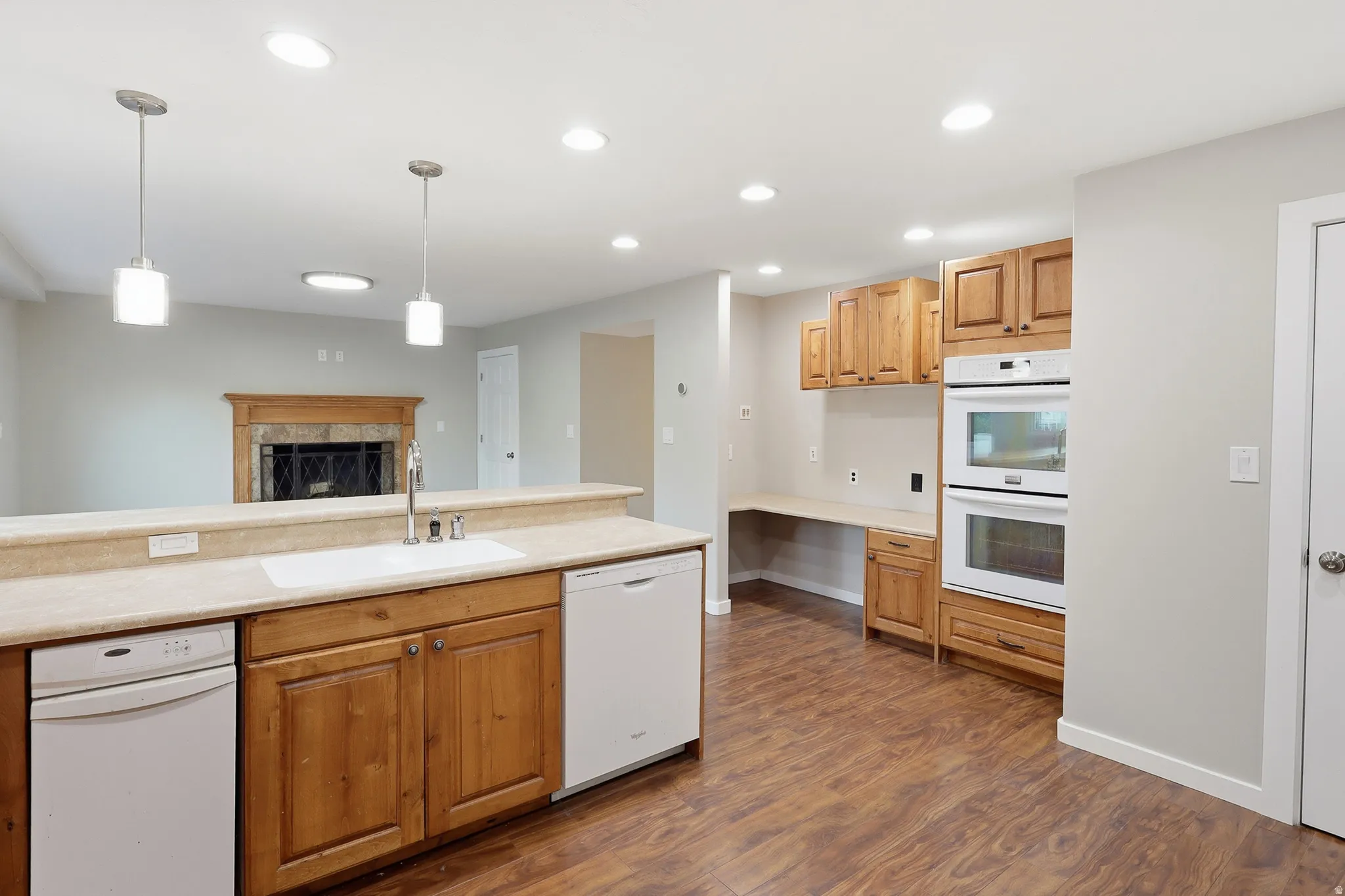 Kitchen featuring wood-finish flooring, built-in double oven, wood cabinetry, and an integrated desk area