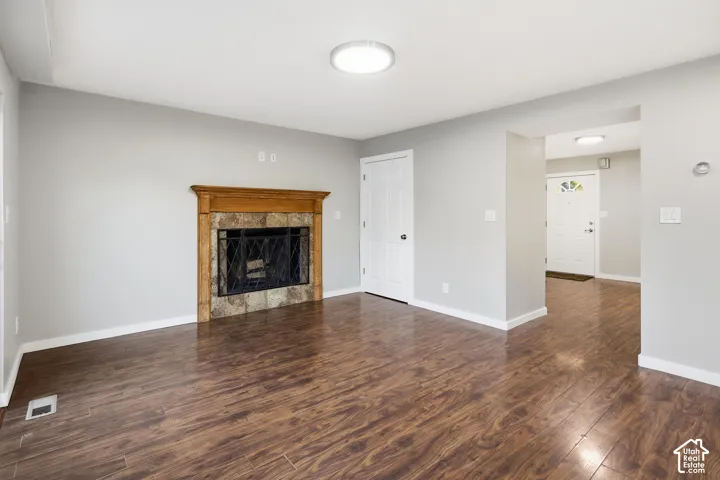 Hardwood-finish flooring, a fireplace with a wood mantle and stone surround, and a ceiling-mounted light fixture