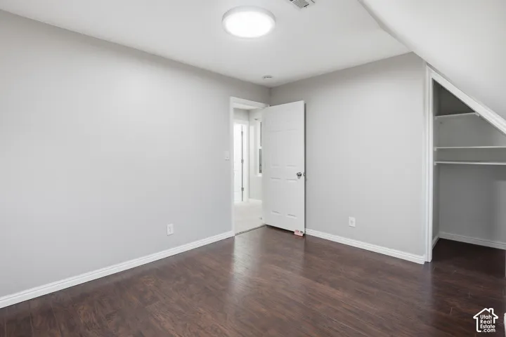 Wood-finish flooring, white baseboards, and built-in closet shelving