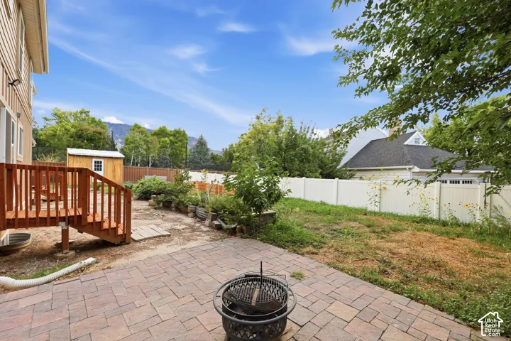 Patio area with paver stones, wooden deck, storage shed, and a privacy fence