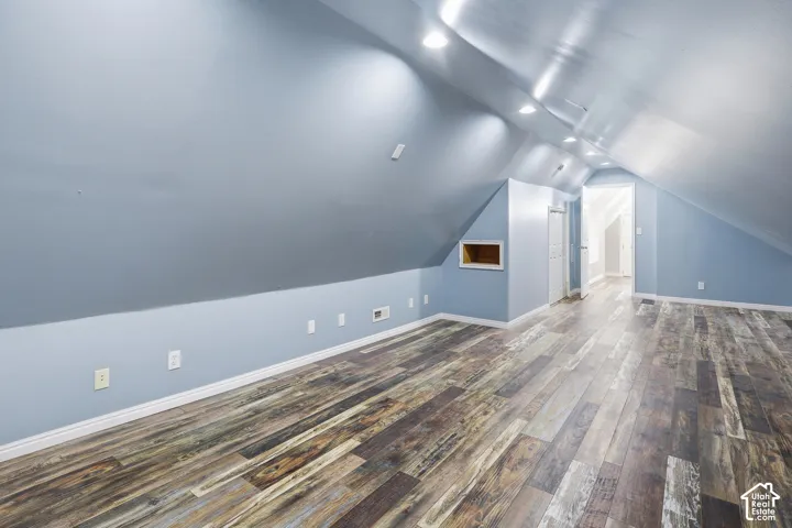 Wood-finish flooring, recessed ceiling lighting, vaulted ceiling, built-in wall niche, and doorway access