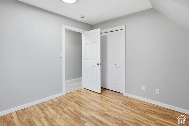 Room featuring wood-finish flooring, light gray walls, a flush-mount ceiling light, and white paneled doors