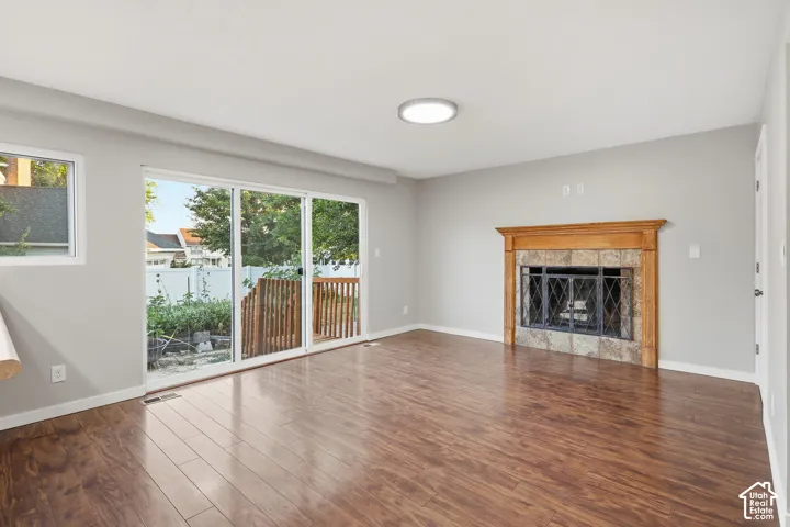 Fireplace with a wood mantle and stone surround, wood-finish flooring, sliding glass door, and a wooden deck