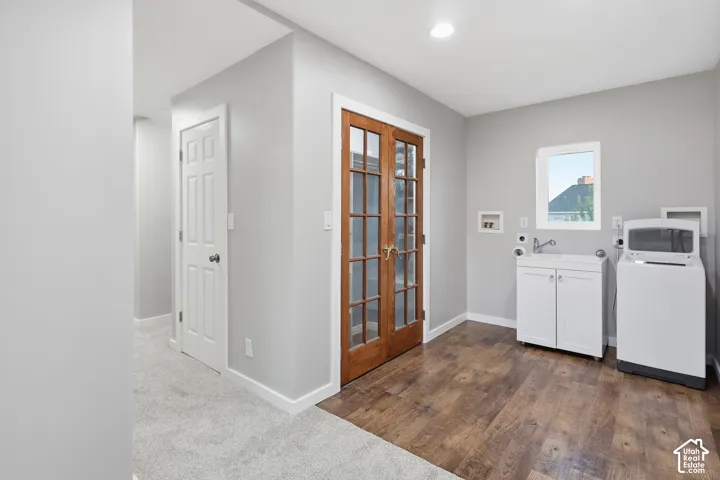 Laundry area featuring wood-finish flooring, a white utility sink cabinet, and a window